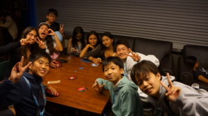 Students enjoying a card game and smiling together, showing fun and friendship during study abroad.